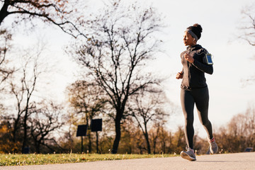 African American female athlete jogging in nature.