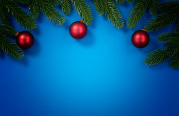 Merry Christmas holiday top circle fir branches and red ornaments border on blue background