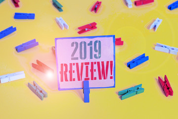 Word writing text 2019 Review. Business photo showcasing remembering past year events main actions or good shows Colored clothespin papers empty reminder yellow floor background office
