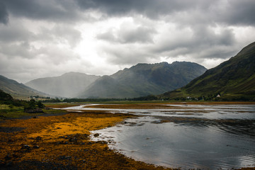 Typical scotland landscape sea view with cloudy weather with yellow seaweed covered rocks in foreground