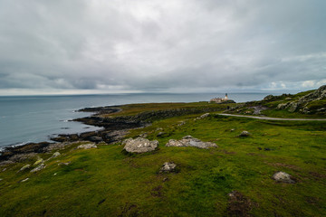 Fototapeta na wymiar View on green grass filled coastal in Scotland near Nest Point famous lighthouse, Isle of Skye
