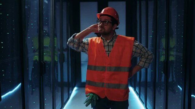Electrical technician standing in middle of server room, inspecting and repairing electricity, experiencing power failure and blackout. Dark data center.