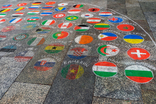 Emblems, flags of different countries painted on the pavement with multicolored crayons.
