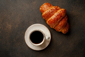 coffee and croissant on a stone table with copy space for your text, early breakfast concept