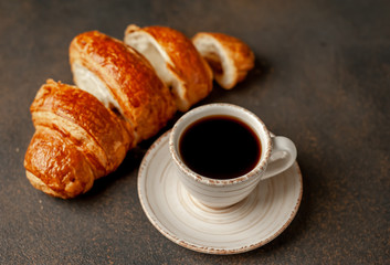 coffee and a large sliced ​​croissant on a stone table, close-up, early breakfast concept