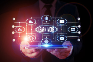 Handwriting text writing Learn More. Conceptual photo Deepen knowledge of the thing you want to do or new skill Male human wear formal work suit presenting presentation using smart device