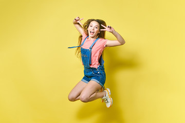 Girlish, funky, happiness, dream, fun, joy, summer concept. Very excited happy cute girl is jumping up, in summer outfit, on yellow background