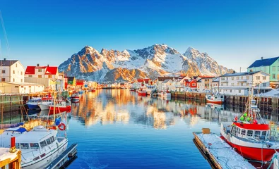 Fotobehang Beautiful Winter nature scene of fishing town on Lofoten Islands in Norway. Amazing sunny landscape of traditional houses rorbu and fishing boats in harbor. © Feel good studio