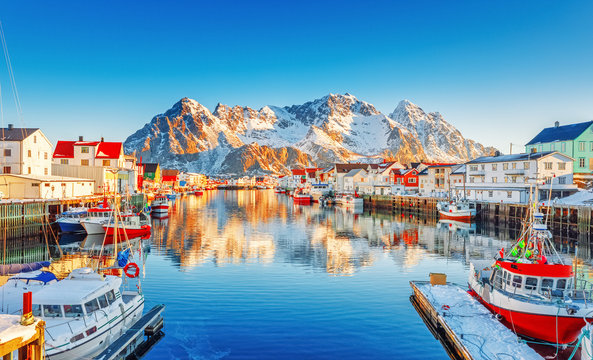 Beautiful Winter nature scene of fishing town on Lofoten Islands in Norway. Amazing sunny landscape of traditional houses rorbu and fishing boats in harbor.