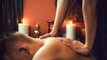 Obraz na płótnie Canvas Asian woman Thai massaging beautiful adult man at spa salon