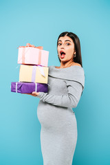 shocked pregnant pretty girl holding presents isolated on blue