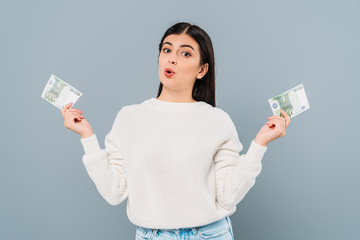 surprised pretty girl in white sweater holding euro banknotes isolated on grey