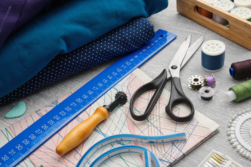 Tailoring scissors, measuring tape, spools of thread, patterns on paper, seamstress cutting knife,...