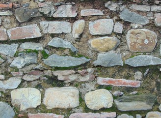 Old stone wall with moss and stones. Masonry walls in medieval Italian style. Close-up, background.