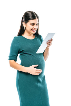 smiling pregnant girl looking at fetal ultrasound images isolated on white