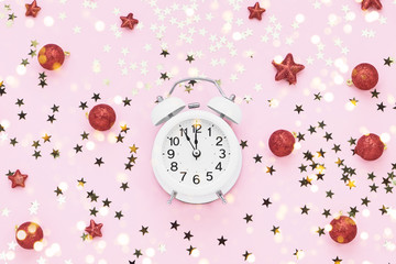 Christmas decoration and white vintage alarm clock on pink background. Top view, copy space