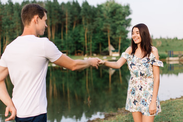 Young loving couple dancing near lake.