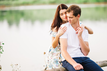 Young loving couple hugging near lake on sunset.