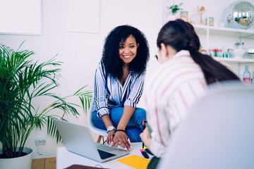 Smiling black woman listening to talkative coworker