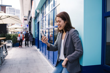 Laughing ethnic woman speaking via phone on street