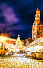 Night Cityscape with Christmas Market at Dome Cathedral square in Winter Riga, Latvia. Advent Fair...