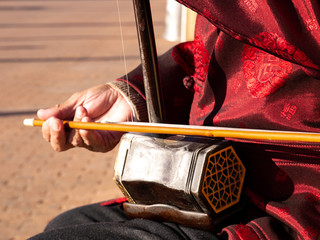 Asian senior man playing an erhu in the street
