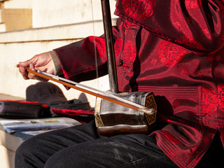 Asian senior man playing an erhu in the street
