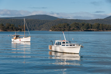 Fototapeta premium Two fishing boats on a lake with mountains in the distance