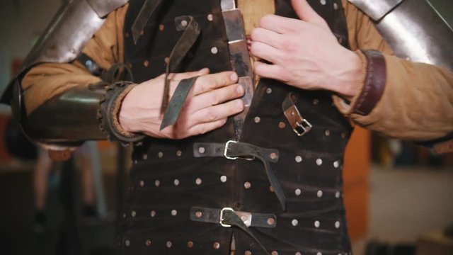 Men putting on a knight armour in the dressing room - putting on a jacket