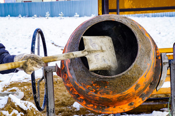home concrete mixer on the street, shovel pouring sand, the process of preparing cement