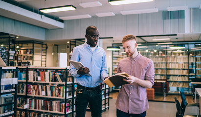 Multiracial students standing with books in library
