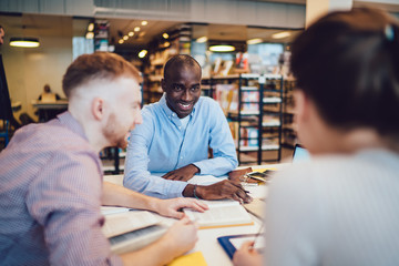 Obraz premium Delighted friends doing homework in library