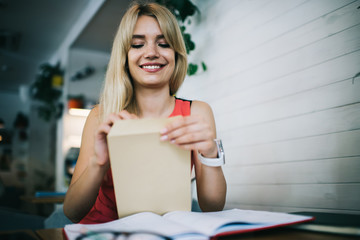 Cheerful young woman opening envelope in office