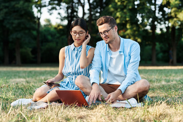 young couple sitting on grass in park