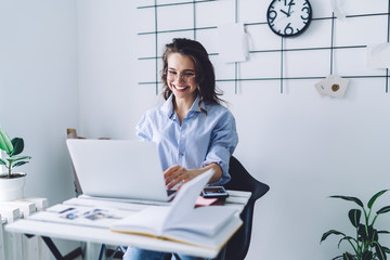 Happy woman working at laptop while sitting at desk
