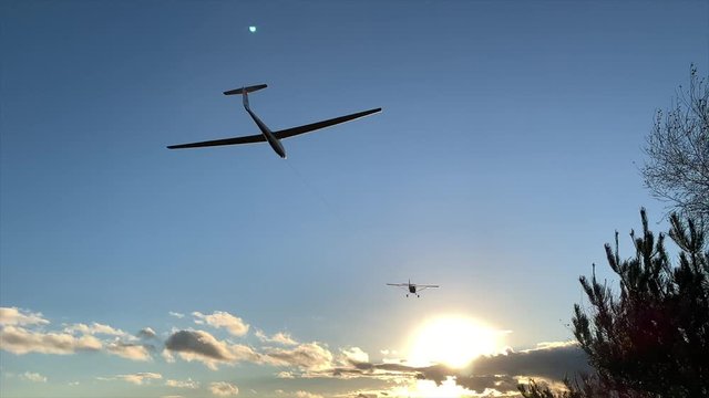 Slow motion glider and plane into sunset