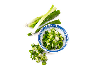 chopped spring onion, scallions, in a blue dish on white background