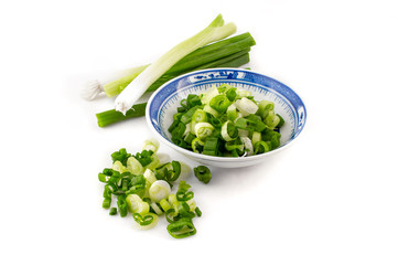 chopped spring onion, scallions, in a blue dish on white background
