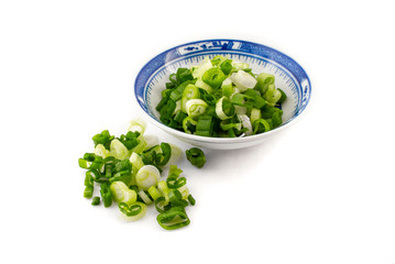 chopped spring onion, scallions, in a blue dish on white background