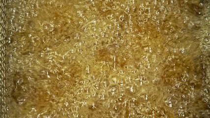 Deep fryer with boiling oil and chicken. Large, deep fryer container for frying food Buffalo wings. Restaurant deep fryer chicken wing deep fried on hot oil. Chicken wings in breading.