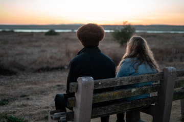 Young Man and Woman on Bench at Sunset
