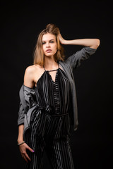 Fototapeta premium Young beautiful woman wearing in black overalls and cardigan posing over black background, top view. Studio shot of brunette woman against isolated background