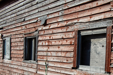 Old red barn exterior wall with three worn windows.