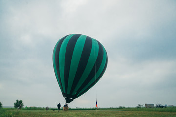 Inflating, unpack and flying up hot air balloon watermelon. Burner directing flame into envelope. Take off aircraft fly in morning blue sky. Start hot air burning to inflate gas fire to air balloon.