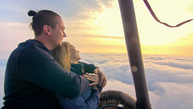 Adventure love couple on hot air balloon watermelon. Man and woman kiss hug love each other. Burner directing flame into envelope. Fly in morning blue sky. Happy people take selfie in hot air ballon.