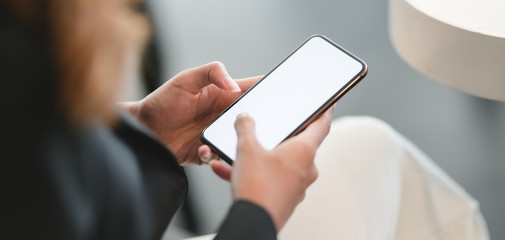 Cropped shot of businesswoman using smartphone in blurred office room