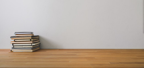 Cropped shot of comfortable workspace with notebook and copy space on wooden table and white wall