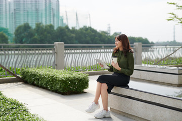 Pretty young woman with beautiful smile using tablet in the park