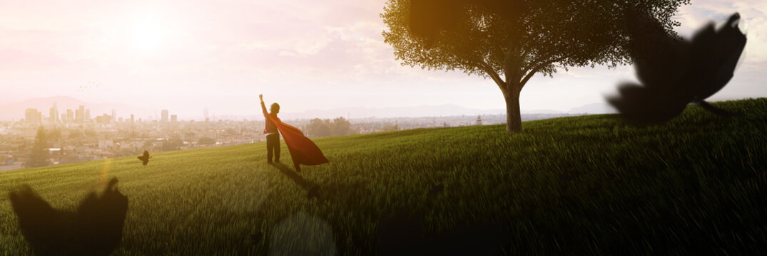 boy dreaming of being superhero in the park looking at the city