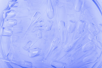 Glass medical ampoule vial for injection. Medicine is liquid sodium chloride with of aqueous solution in ampulla. Close up. Bottles ampule multicolor on background color and water. Human plasma.
